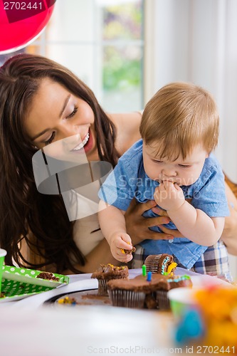 Image of Mother Looking At Baby Boy Eating Cupcake