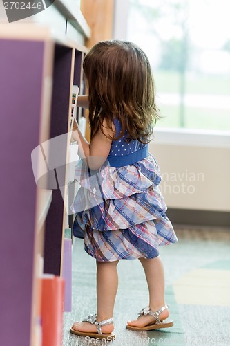 Image of Girl Selecting Book From Bookshelf