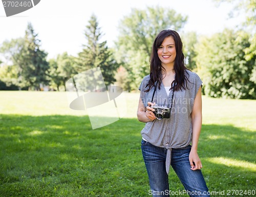 Image of Attractive Woman Holding Digital Camera In Park