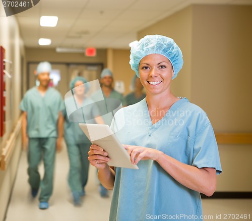 Image of Doctor With Digital Tablet While Team Walking In Hospital Corrid