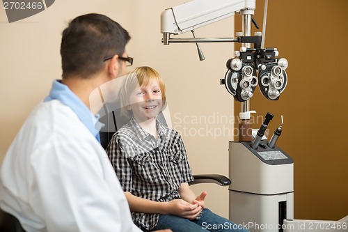 Image of Boy Smiling While Sitting With Optometrist In Store