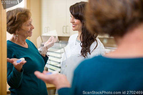 Image of Optometrist Looking At Woman Holding Contact Lens