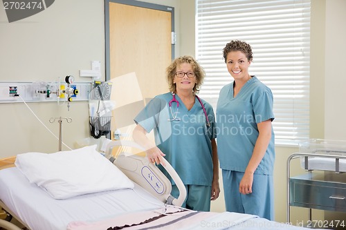 Image of Nurses Standing Together By Bed In Hospital Room