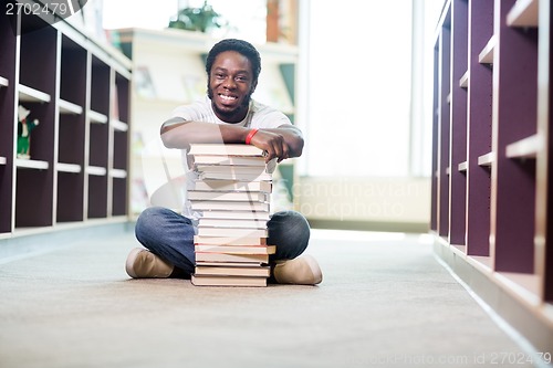 Image of Confident Student With Stacked Books Sitting In Library