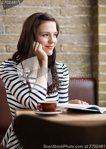 Image of Woman With Hand On Chin Looking Away In Coffeeshop