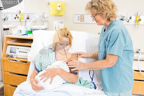 Image of Nurse Helping Woman In Breast Feeding Baby In Hospital