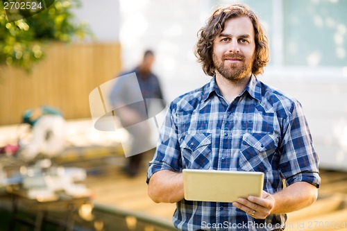 Image of Manual Worker Holding Digital Tablet With Coworker Working In Ba