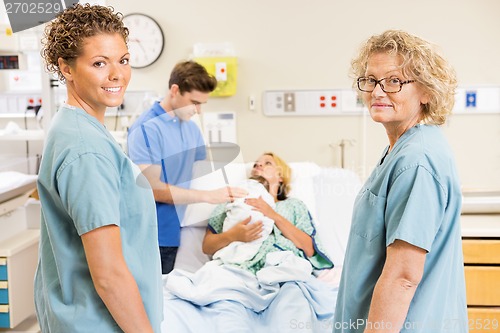 Image of Successful Nurses Standing Against Couple With Baby In Backgroun