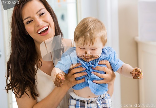 Image of Mother Holding Baby Boy With Cake Icing On Face