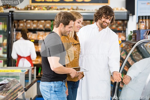 Image of Salesman Assisting Couple In Buying Meat