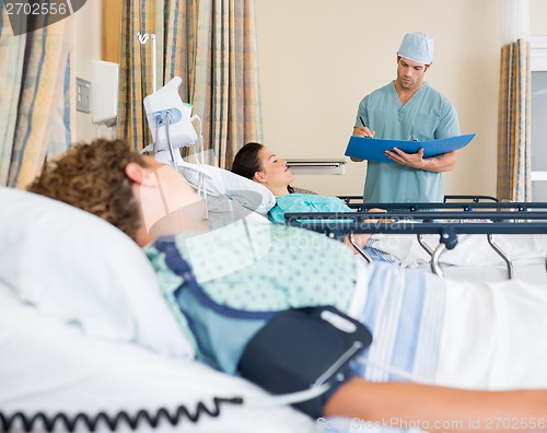 Image of Patient's Lying On Bed While Nurse Examins Report