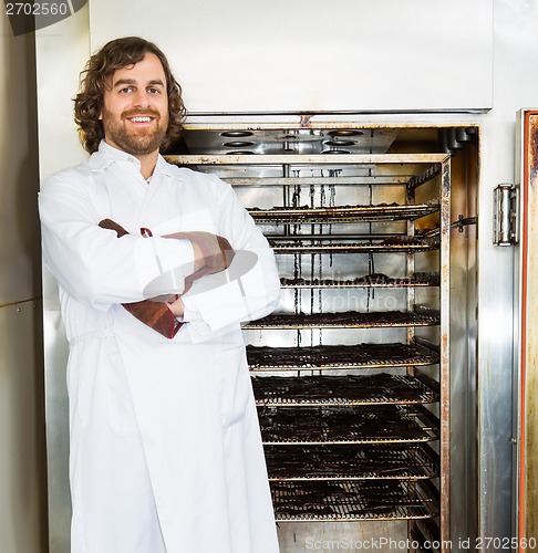 Image of Butcher Standing Arms Crossed In Front of Smoker