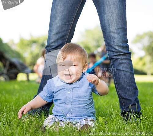 Image of Cute Baby Boy Sitting In Front Of Mother In Park