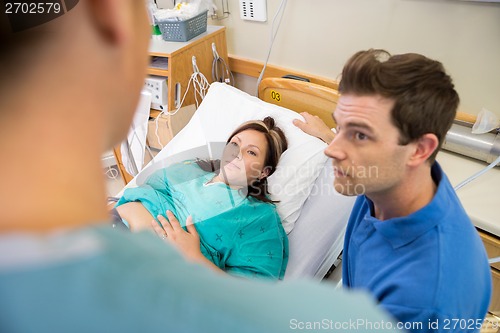 Image of Pregnant Woman And Husband Looking At Nurse In Hospital