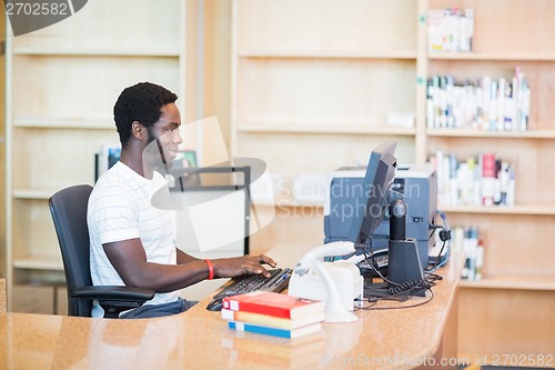 Image of Librarian Working On Desktop PC In Library