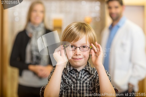 Image of Boy Trying Glasses With Optometrist And Mother At Store