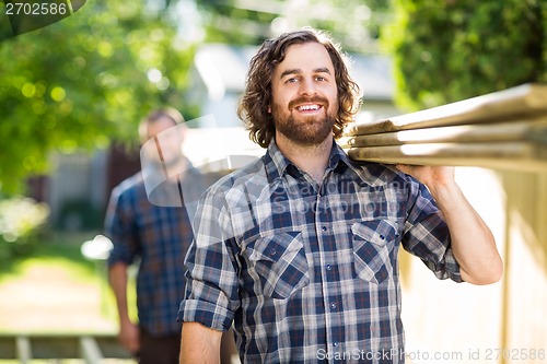 Image of Happy Carpenter With Coworker Carrying Planks Outdoors