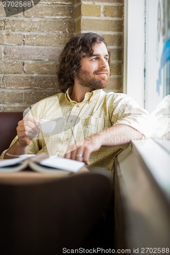 Image of Man With Coffee Cup Looking Through Window In Cafe