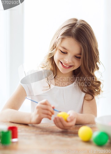 Image of smiling little girl coloring eggs for easter