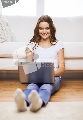 Image of smiling teenage girl with laptop computer at home