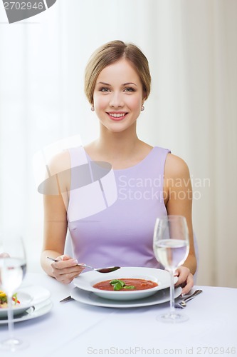 Image of smiling young woman eating appetizer at restaurant