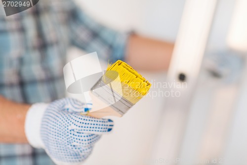 Image of close up of male in gloves holding paintbrush