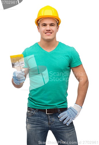 Image of smiling manual worker in helmet with paintbrush