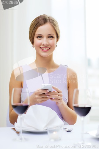 Image of smiling woman with smartphone at resturant