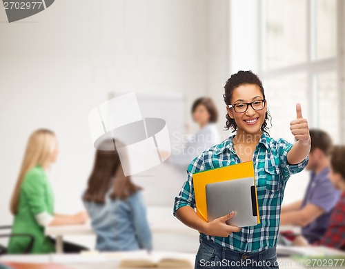 Image of student in eyeglasses with folders and tablet pc