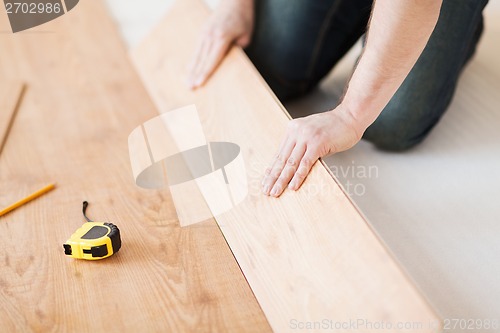 Image of close up of male hands intalling wood flooring