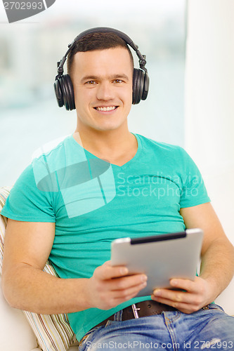 Image of smiling man with tablet pc and headphones at home