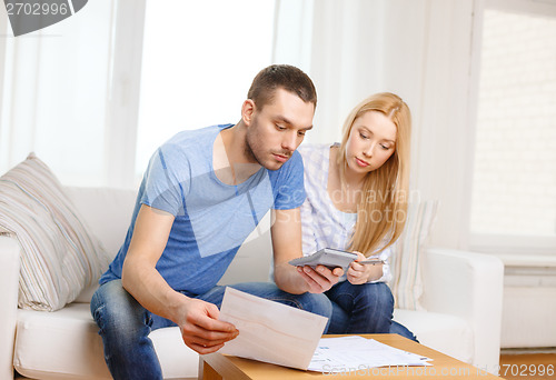 Image of busy couple with papers and calculator at home