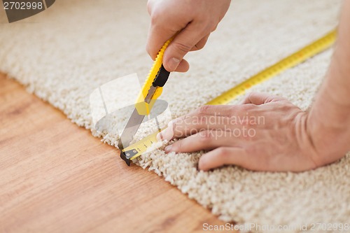 Image of close up of male hands cutting carpet