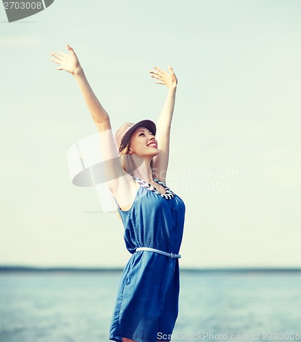 Image of girl with hands up on the beach