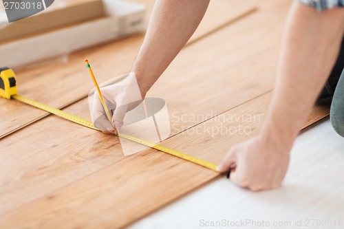 Image of close up of male hands measuring wood flooring