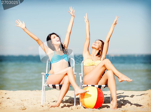 Image of girls sunbathing on the beach chairs