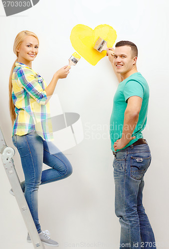 Image of smiling couple painting small heart on wall