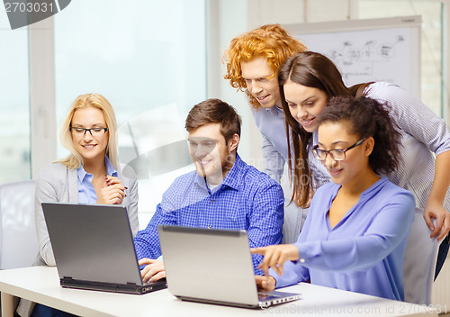 Image of smiling team with laptop computers in office