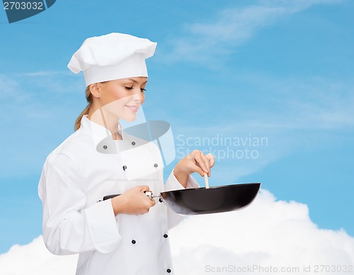 Image of smiling female chef with pan and spoon