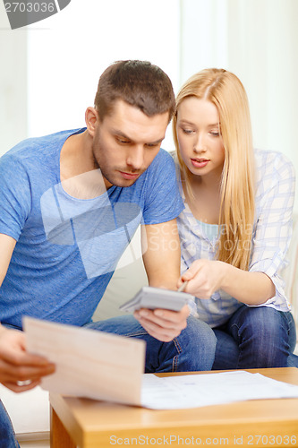 Image of busy couple with papers and calculator at home