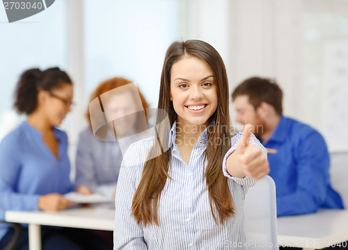 Image of smiling young businesswoman showing thumbs up