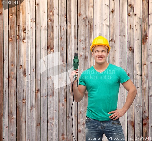 Image of smiling manual worker in helmet with drill machine