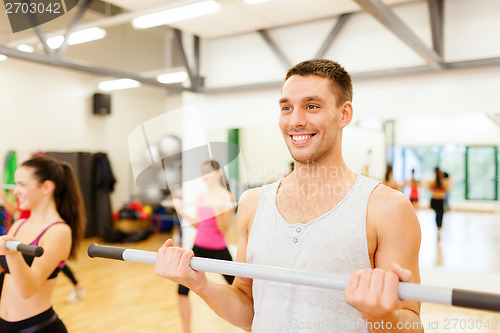 Image of group of smiling people working out with barbells