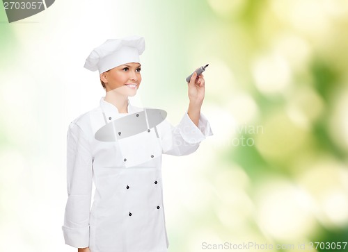 Image of smiling female chef writing something on air