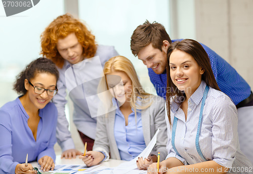 Image of smiling creative team looking over clothes designs