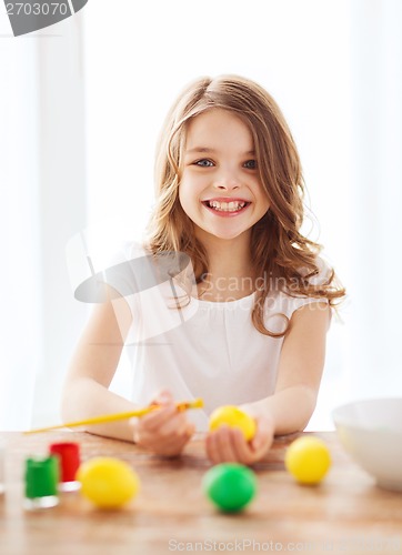 Image of smiling little girl coloring eggs for easter