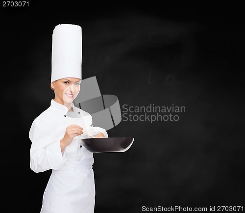 Image of smiling female chef with pan and spoon