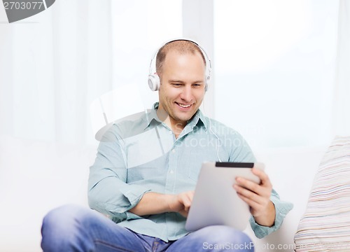 Image of smiling man with tablet pc and headphones at home