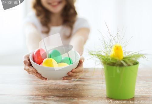 Image of close up of girl holding bowl with colored eggs