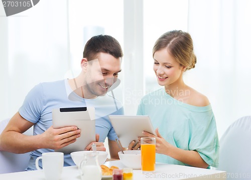 Image of smiling couple with tablet pc reading news